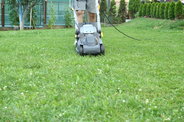 Homem empurrando um cortador de grama — Fotografia de Stock