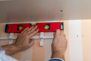 Gardırop kancalarının konumunu balon seviyesinde bir araçla işaretleyen adam