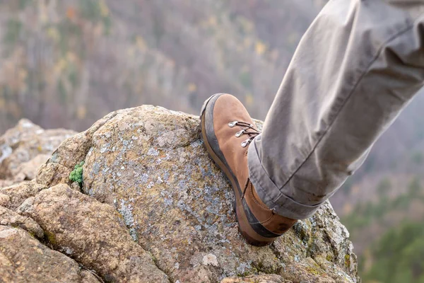 Leg of a man in boot on a rock with a view to hills during hiking