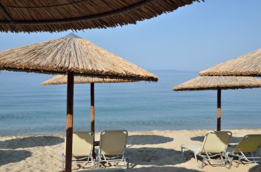 Hasır plaj şemsiyeleri ve sandalyeler çiftlerini plaj