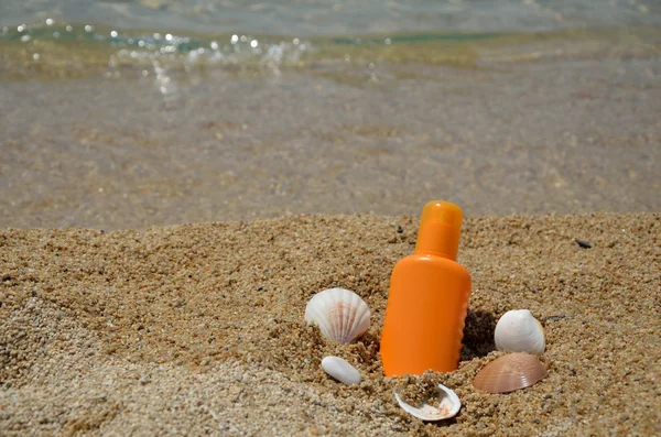 Лосьон для загара с морской раковиной на пляже — стоковое фото