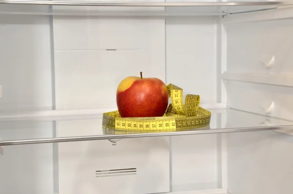 Red apple and measure tape in refrigerator — Stock Photo, Image