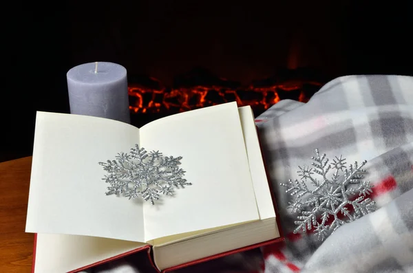 Açık kitap, kar tanesi ve şömine