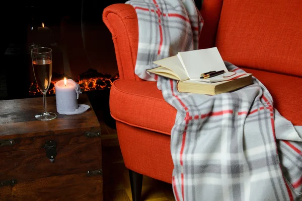 Couverture, livres, bloc-notes et stylo sur fauteuil avec vin, bougie et — Photo