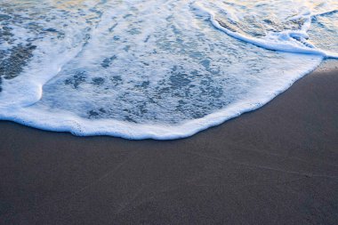 Kum arka planında beyaz köpüklü koyu mavi dalga. iyi akşamlar