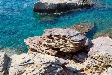 Gök mavisi deniz suyunda ufalanan kaya katmanları