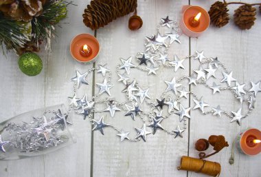 Mumlar, ananaslar, fındıklar ve tarçın çubuklarıyla çevrili, içinden yıldızlar çıkan şampanya kadehli masa dekorasyonu..