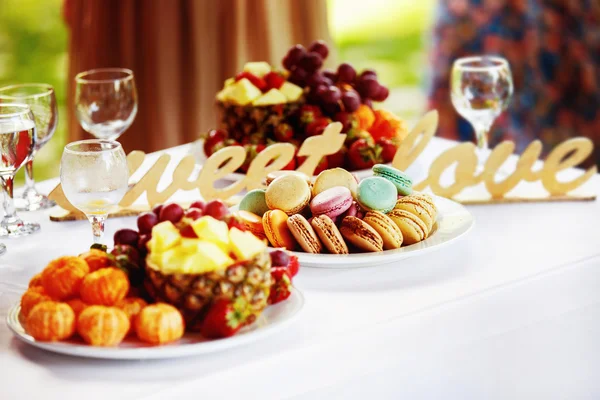 Closeup image of fresh fruits and berries and cookies at a white table background.