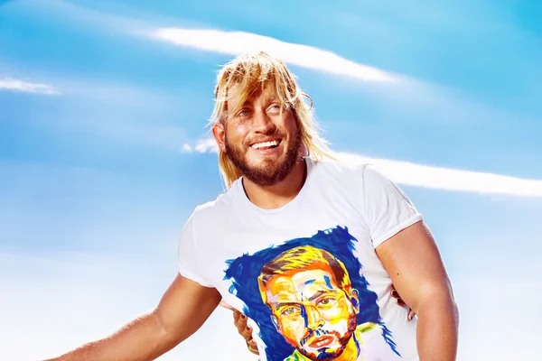 Closeup portrait of happy positive smiling young man with beard covered by woman hair at bright summer sky background.