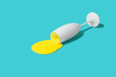 Asgari bileşim, beyaz şampanya bardağından dökülen sarı sıvı, güneşli mavi masa. Gerçek parti arka planı fikri.