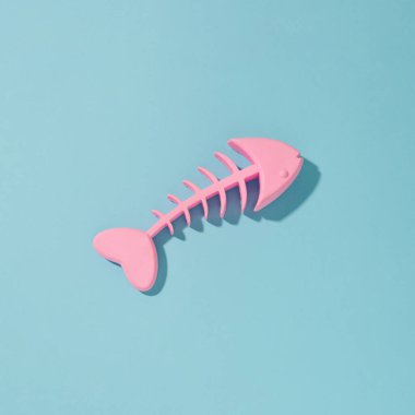 Güneşli mavi arka planda pembe balık iskeleti olan minimum bileşim.