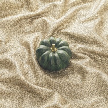 Parlak ipek çarşafta üç koyu yeşil balkabağı olan yaratıcı sonbahar arkaplanı. Minimum konforlu tatil kompozisyonu.