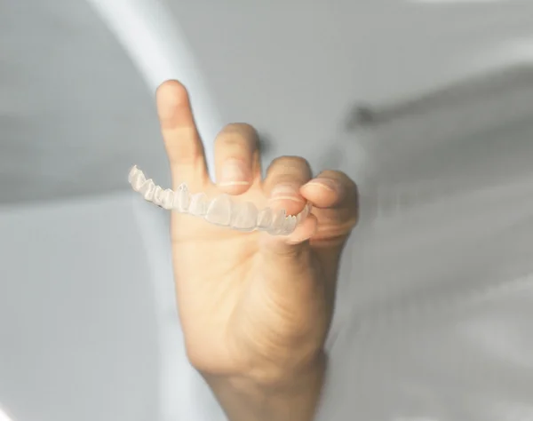 Frau hält unsichtbare Zahnspangen in der Hand — Stockfoto