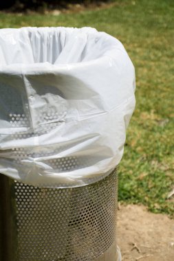 Parktaki çöp tenekesinde beyaz plastik torba var. Kimse yok.