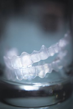 Kristal bir bardağın içinde saydam diş hizalayıcısı. Kimse yok.