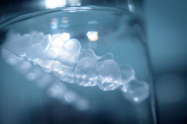 Kristal bir bardağın içinde saydam diş hizalayıcısı. Kimse yok.