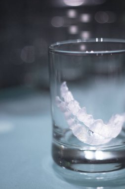 Kristal bir bardağın içinde saydam diş hizalayıcısı. Kimse yok.
