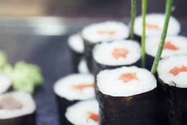 Siyah bir tabakta çeşitli suşi yemekleri. Kimse yok.