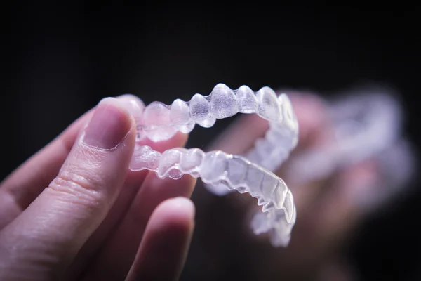 Woman hand holding invisible orthodontics — Stock Photo, Image