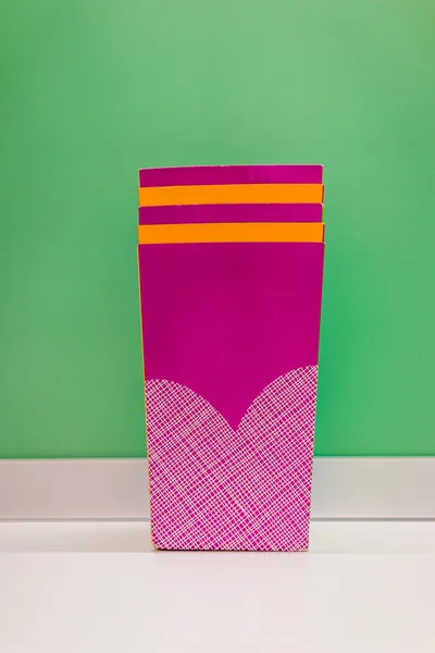 Karton kaplar yeşil bir duvara yığılmış.