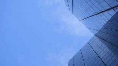 Gökyüzünde uçan bulutlar ve şirket başarısını temsil eden büyük cam bir binaya yansıtılıyor. Şehir merkezindeki ofis binası aşağıdan vuruldu..