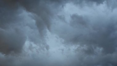 Fırtınalı bulutların fırtınayı başlatacak büyük gri bir bulut oluşturup bir araya gelmesinin hızlandırılmış görüntüleri. Bu korkunç fırtınada gri ve mavi baskın renkler.