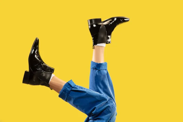 黄色の背景に隔離された黒いスタイリッシュな靴の男の足. — ストック写真