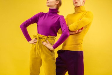 Sarı arka planda izole edilmiş şık giyimli iki kişinin kırpılmış görüntüsü..