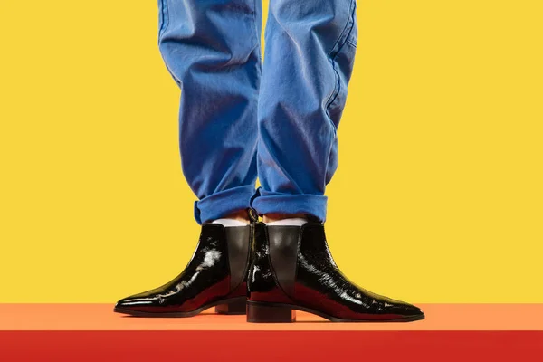 Młody mężczyzna mody nogi w niebieskich dżinsach i czarne buty na czerwonym piętrze — Zdjęcie stockowe