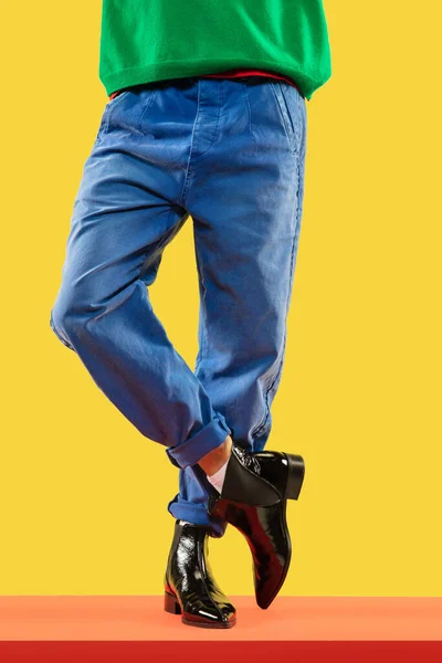 Молоді модні чоловічі ноги в блакитних джинсах і чорних черевиках на червоній підлозі — стокове фото