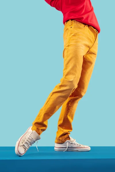 Unga herrben i bruna byxor och vita sportskor på blått golv — Stockfoto