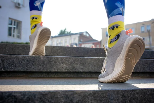 Close-up pernas femininas em leggins azuis e meias amarelas correndo lá em cima ao ar livre. — Fotografia de Stock