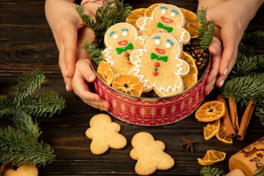 Kadın ve çocuk elleri Noel hediyesi olarak zencefilli bisküvi kutusunu tutuyor..