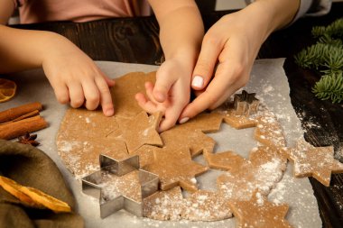 Yakın plan çocuk ve kadın elleri şenlikli kurabiyeler ve zencefilli kurabiye yapıyorlar..