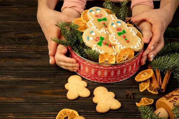 Kadın ve çocuk elleri Noel hediyesi olarak zencefilli bisküvi kutusunu tutuyor..
