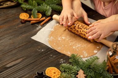 Yakın plan çocuk ve kadın elleri merdaneyle neşeli kurabiyeler yapıyor..