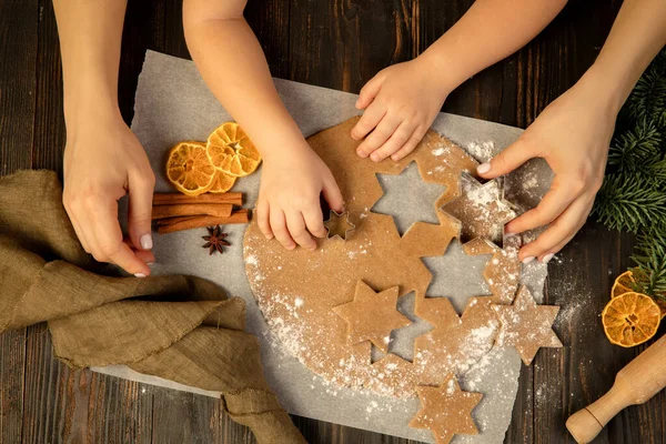 Yakın plan çocuk ve kadın elleri şenlikli kurabiyeler ve zencefilli kurabiye yapıyorlar..