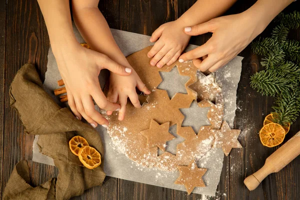 Yakın plan çocuk ve kadın elleri şenlikli kurabiyeler ve zencefilli kurabiye yapıyorlar..