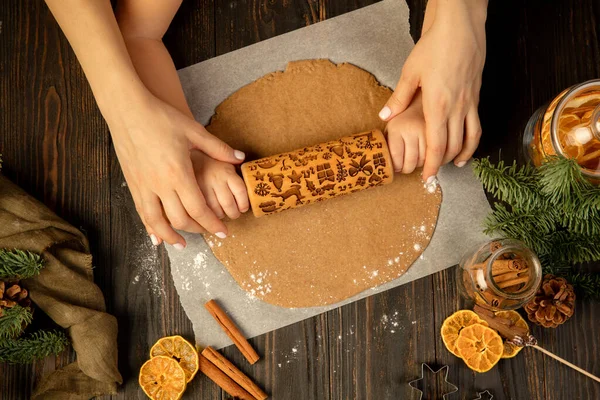 Yukardan bakan çocuk ve kadın elleri merdaneli neşeli kurabiyeler yapıyor..