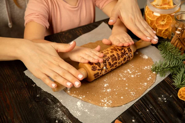 Yakın plan çocuk ve kadın elleri merdaneyle neşeli kurabiyeler yapıyor..