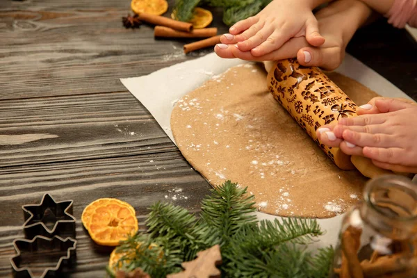 Yakın plan çocuk ve kadın elleri merdaneyle neşeli kurabiyeler yapıyor..