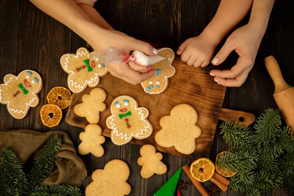 Yakın plan çocuk ve kadın elleri festival kurabiyeleri ve zencefilli kurabiye erkekler.
