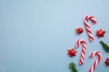 Beyaz ve kırmızı baston şekerler ve mavi arka planda Noel ağacı süslemeleri..