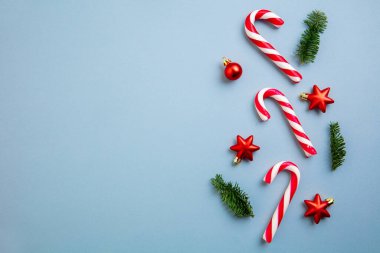 Noel süsleri, baston şekerler ve kırmızı yıldızlar mavi arka planda..