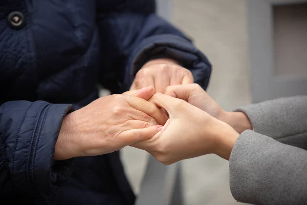 Primo piano di giovani mani femminili che tengono mani di donna anziana. — Foto Stock