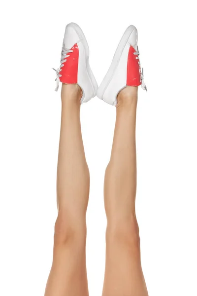 Close-up szczupłe kobiece nogi w białym obuwiu izolowane nad tłem studio — Zdjęcie stockowe