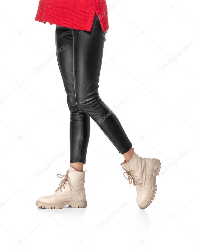 Slender female legs in black leggings and boots isolated on white background