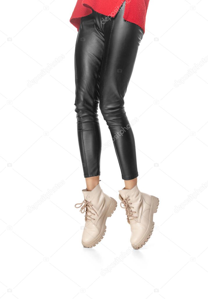 Shapely female legs in leather leggings and boots isolated on white background