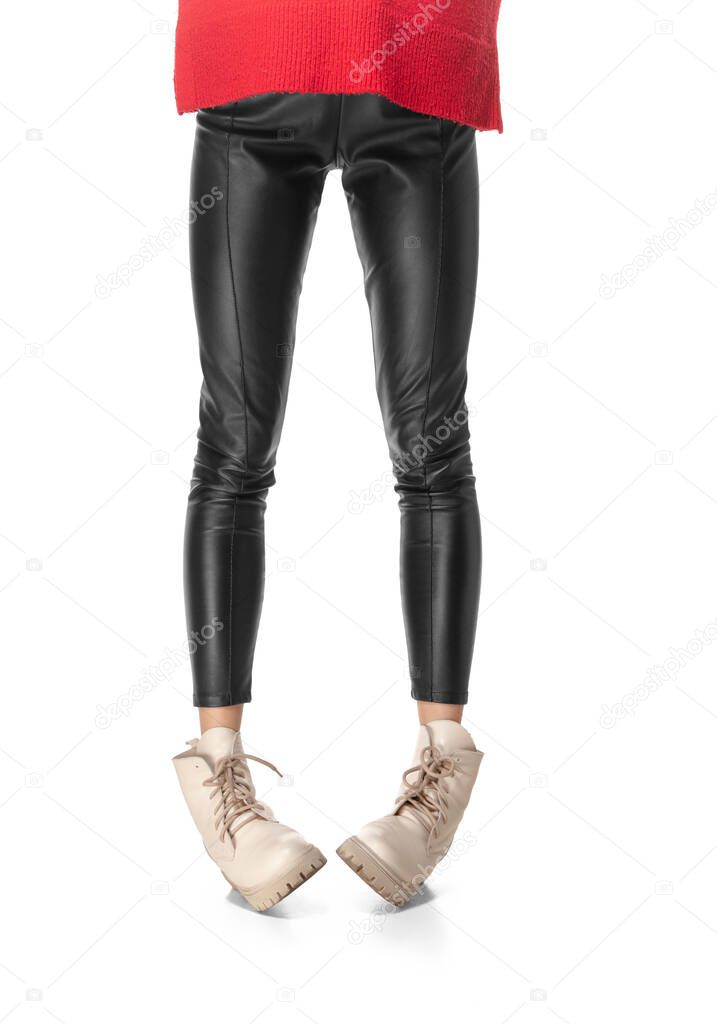 Slim long female legs in black leggings and boots isolated on white background