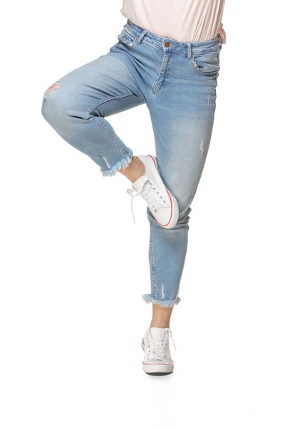 Schöne weibliche Beine in blauen Jeans und Sportschuhen isoliert auf weißem Hintergrund — Stockfoto